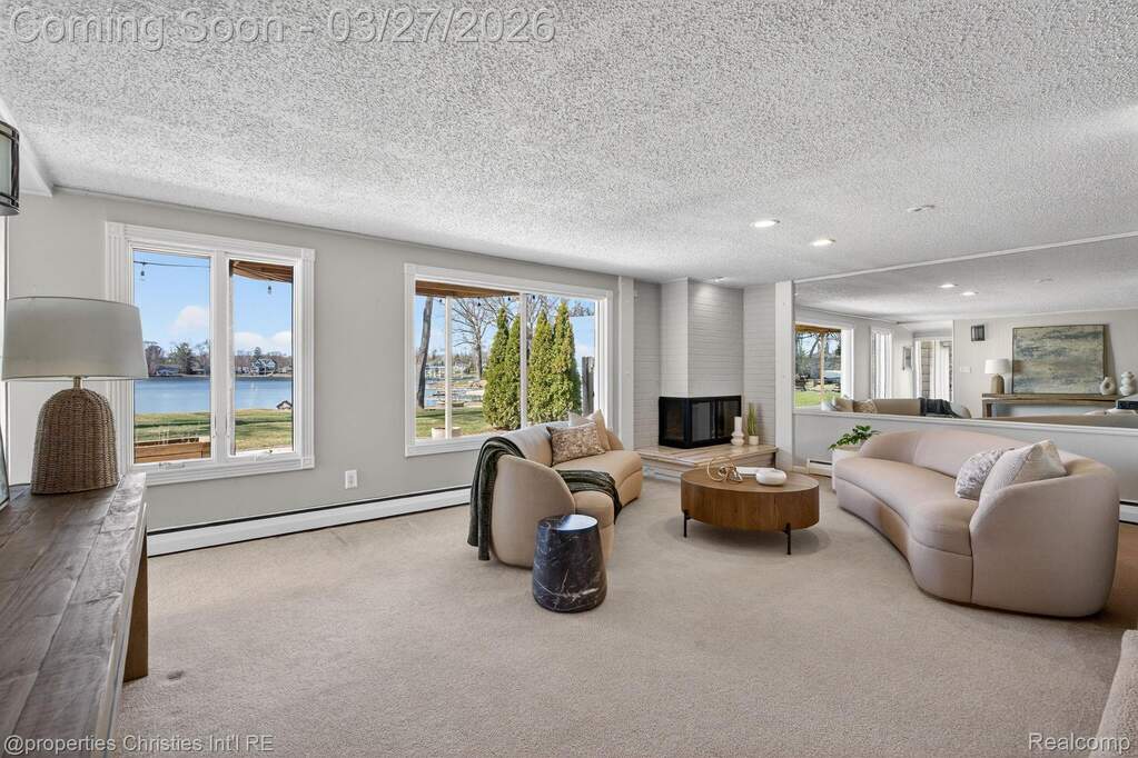Living room featuring a baseboard radiator, a water view, a textured ceiling, carpet, and recessed lighting