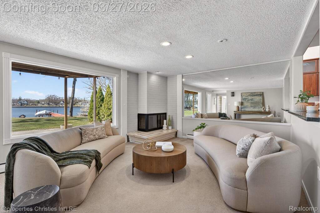 Carpeted living area with a textured ceiling, a water view, a large fireplace, and recessed lighting