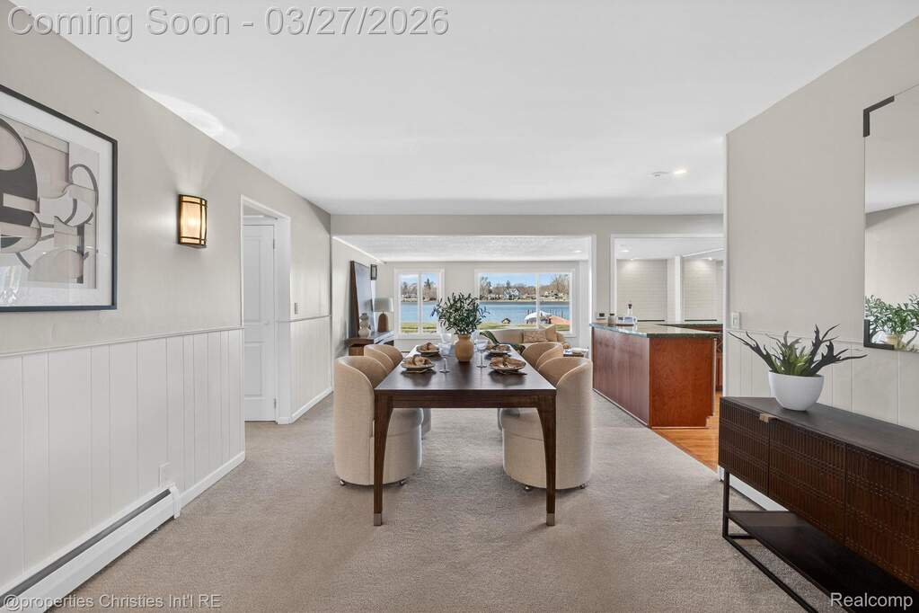 Dining room with a baseboard heating unit, light carpet, and wainscoting