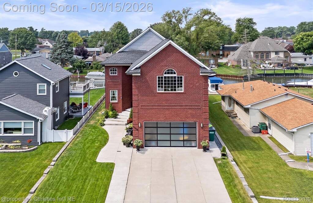 View of front of house with a residential view, an attached garage, brick siding, and concrete driveway