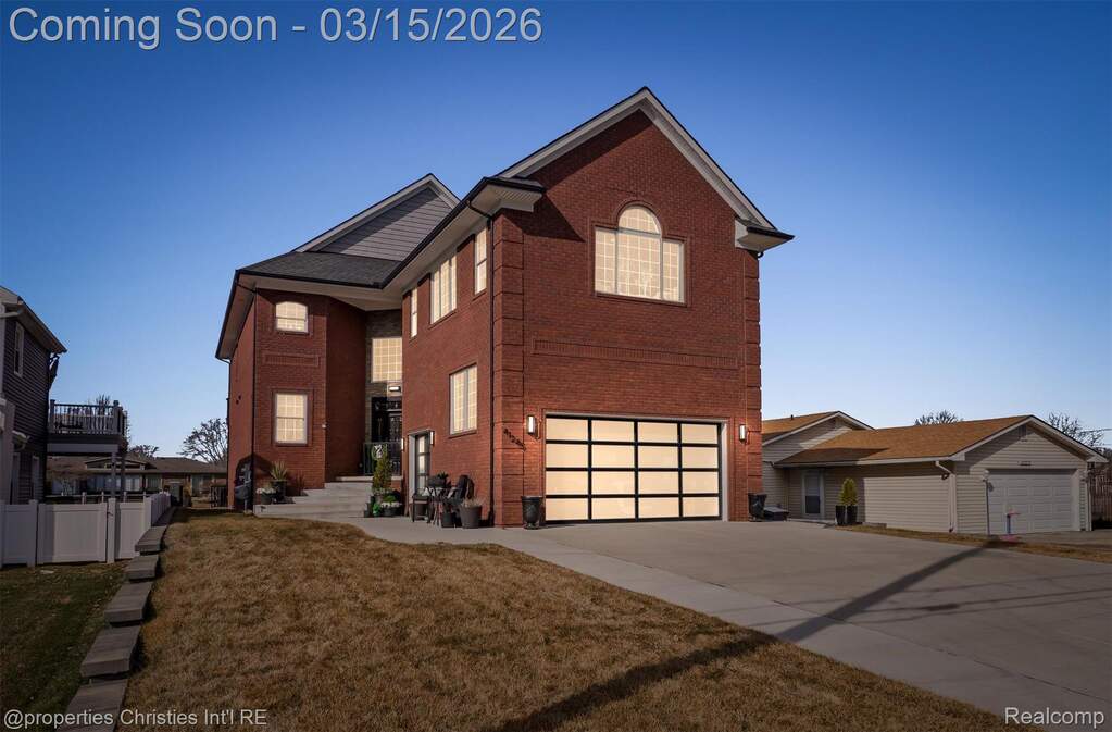 View of front of house with brick siding, a garage, a front yard, and driveway
