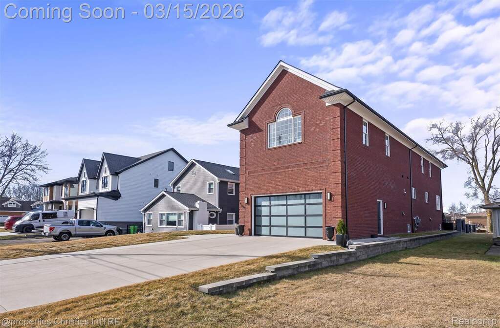 View of home's exterior with brick siding, a garage, concrete driveway, a residential view, and a yard