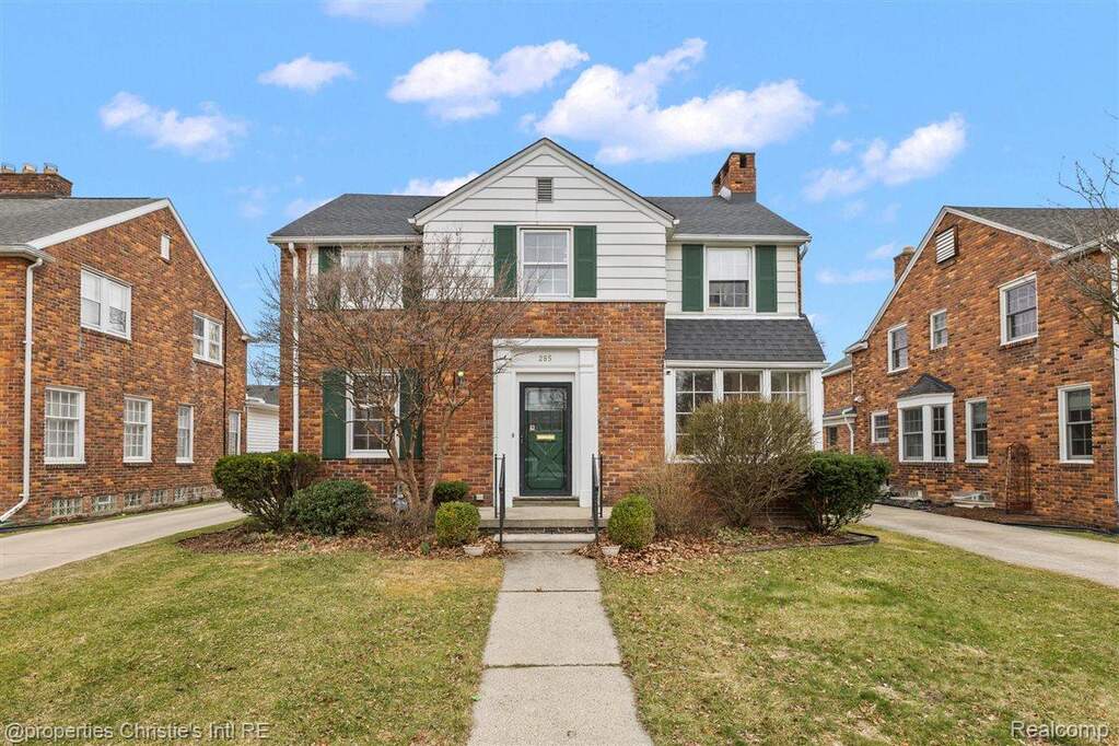 Traditional home with a front yard, a chimney, and brick siding