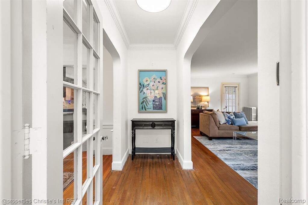 Hallway featuring ornamental molding, dark wood-style flooring, and arched walkways
