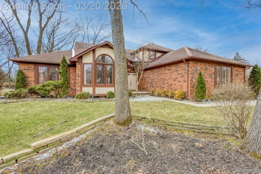 View of front of home featuring brick siding, a shingled roof, a front yard, and a sunroom