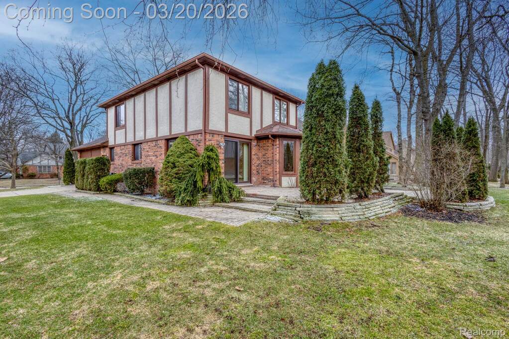 View of front of home with brick siding, a front yard, a patio, and stucco siding
