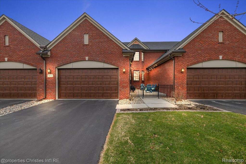 View of front facade with asphalt driveway, brick siding, a front yard, and a garage