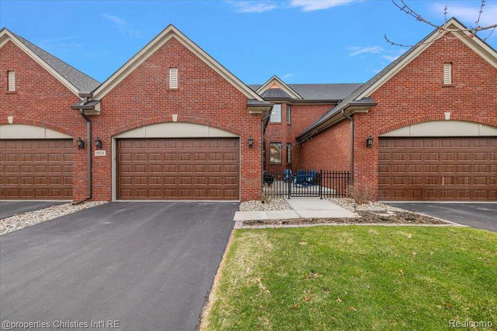 View of front of home featuring asphalt driveway, brick siding, and a garage