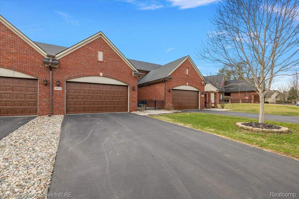 View of front of home with driveway, brick siding, a front yard, and an attached garage
