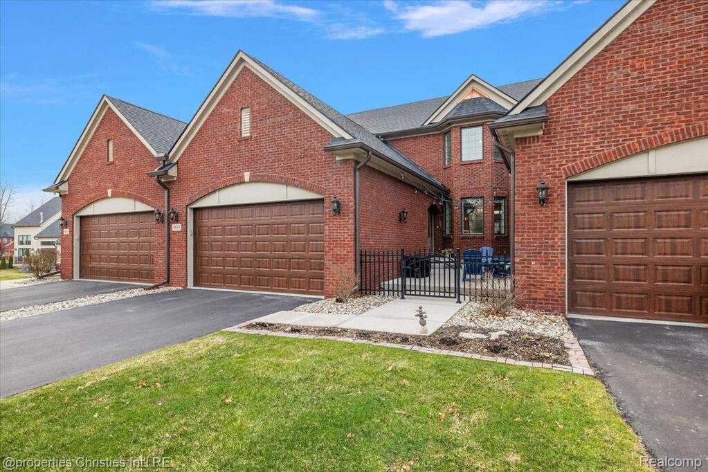 Traditional-style house with brick siding, driveway, a front yard, and an attached garage