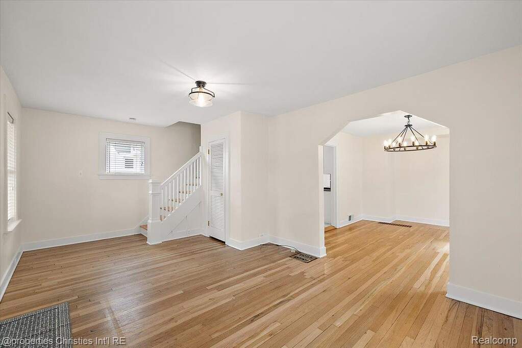 Spare room with light wood-style flooring, arched walkways, and hanging lights