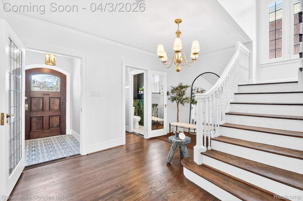 Entryway featuring french doors, dark wood-style flooring, hanging lights, and crown molding