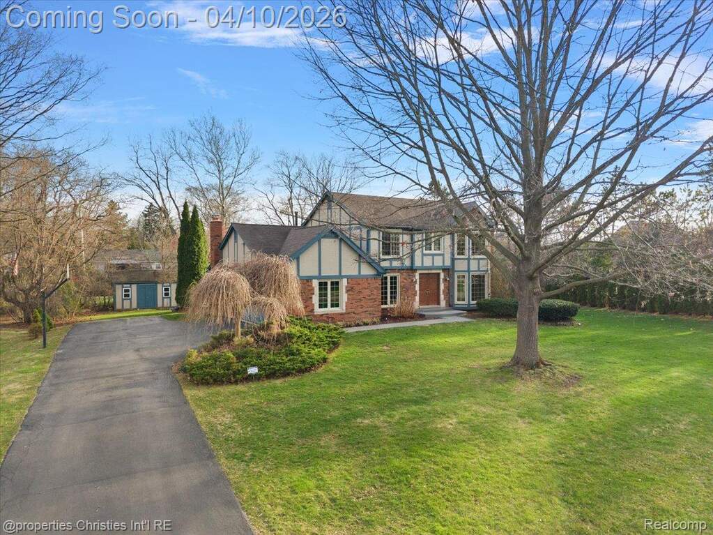 English style home featuring driveway, a front lawn, and brick siding