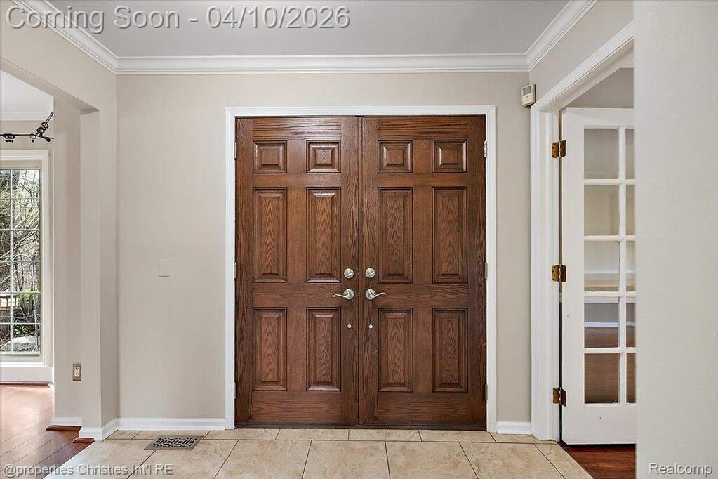Entrance foyer with ornamental molding and light tile patterned flooring