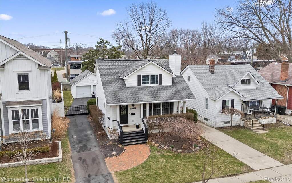 View of front facade featuring a shingled roof, a residential view, and a front lawn