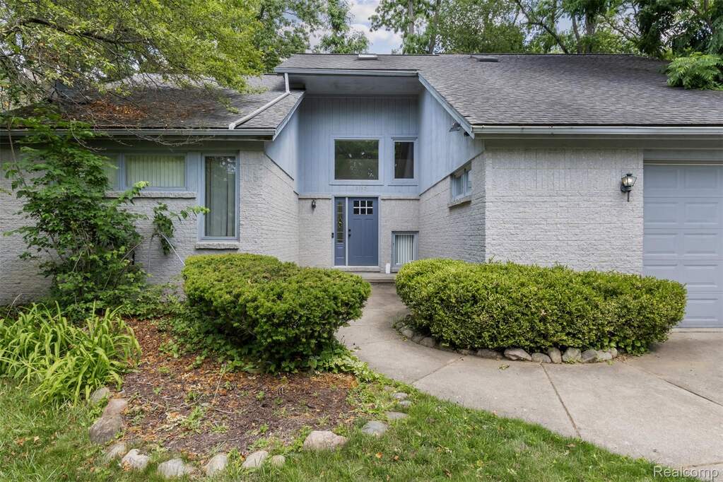 View of front of house with brick siding, an attached garage, and roof with shingles