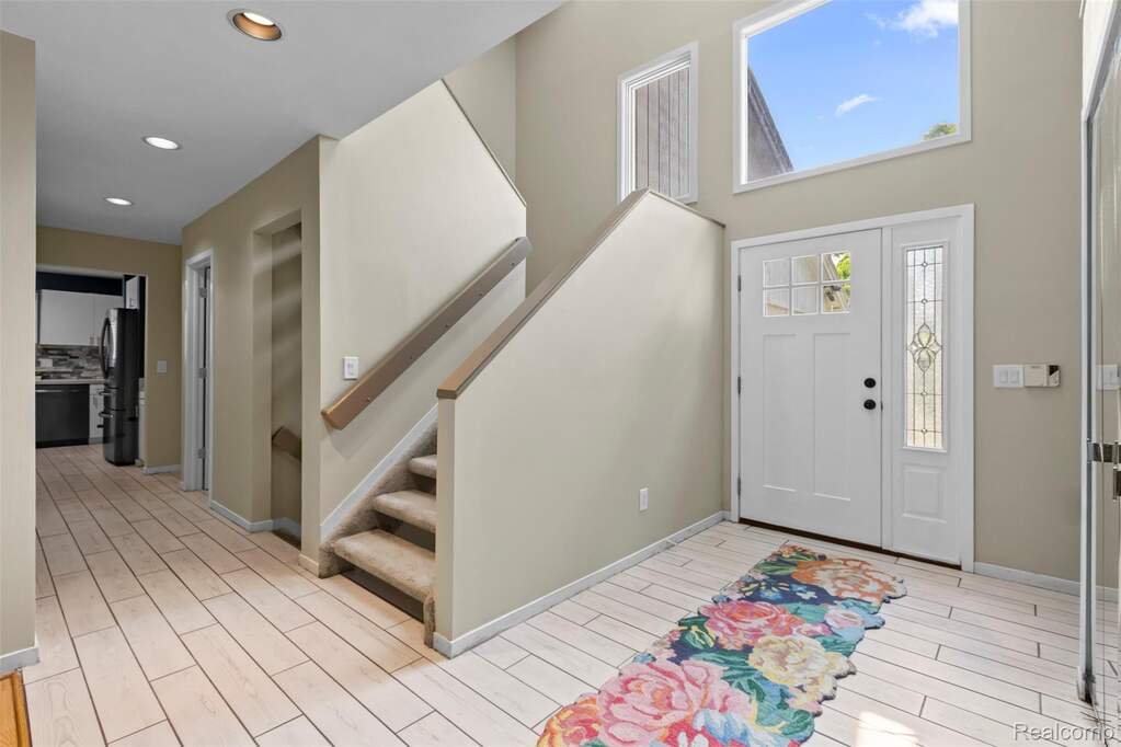 Entryway with wood finish floors, a high ceiling, and recessed lighting