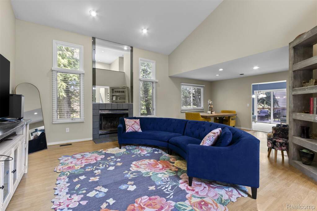 Living area with a fireplace, vaulted ceiling, light wood finished floors, and recessed lighting
