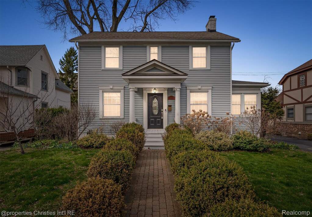 Colonial inspired home featuring a front lawn and a chimney