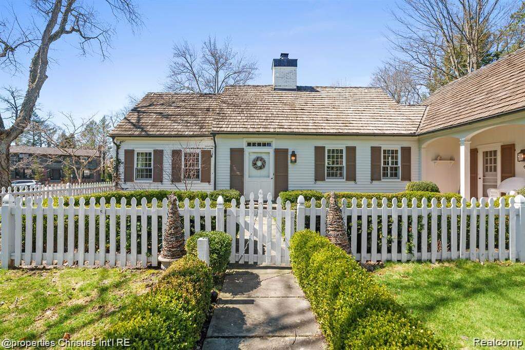 View of front of property with a chimney, a fenced front yard, and a gate