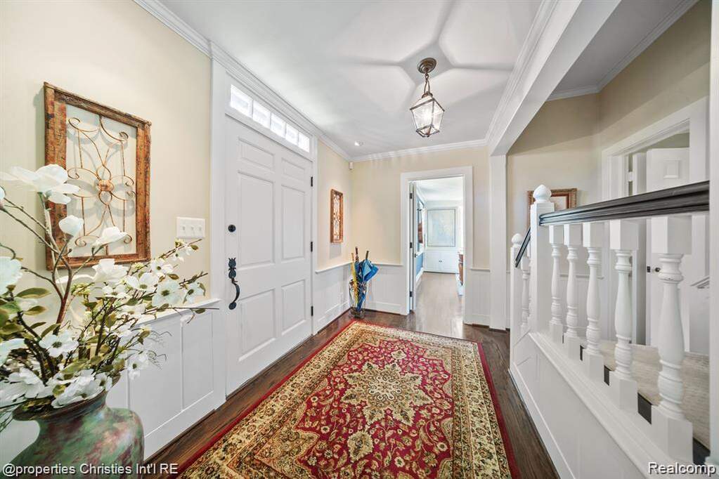 Entrance foyer with healthy amount of natural light, wainscoting, dark wood-style flooring, crown molding, and a decorative wall
