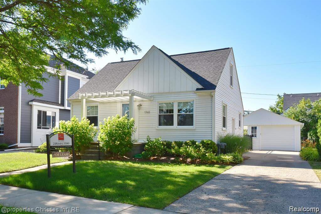 View of front of home featuring board and batten siding, an outbuilding, a detached garage, a front lawn, and roof with shingles