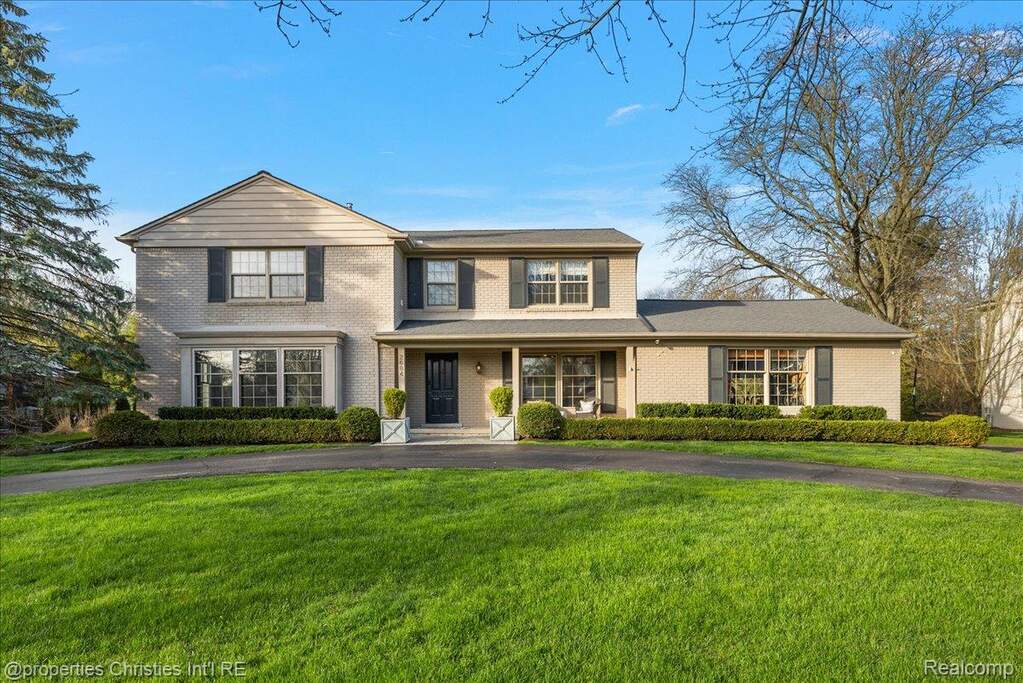 Traditional home with a porch, brick siding, and a front yard