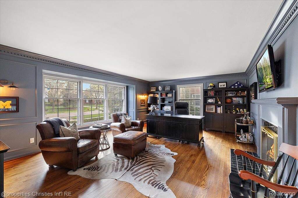 Office space featuring a decorative wall, wood finished floors, a fireplace with flush hearth, and ornamental molding