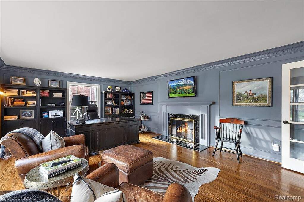 Home office featuring wood finished floors, a high end fireplace, and a decorative wall