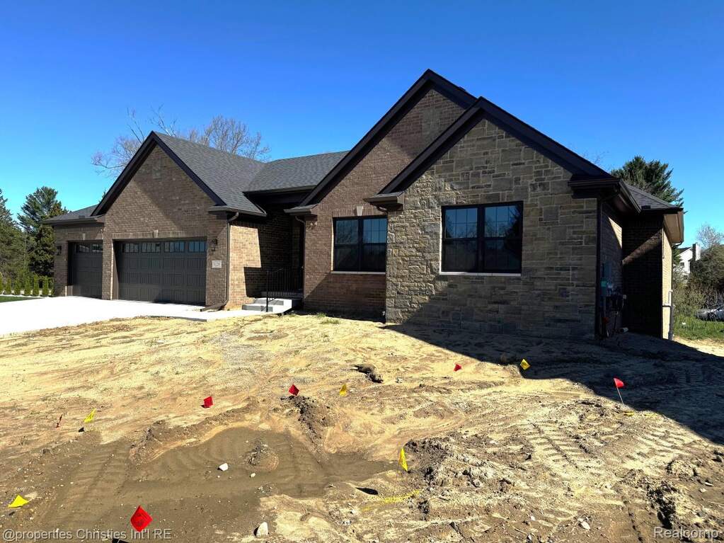 View of front facade with an attached garage, concrete driveway, brick siding, and stone siding