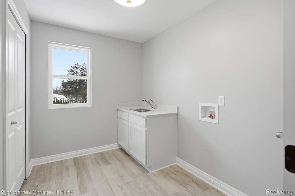 Laundry room with light wood-style floors, washer hookup, and cabinet space