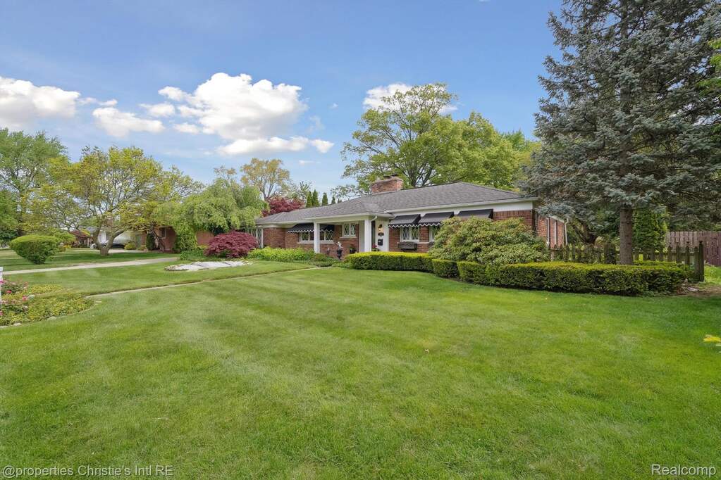 View of front of property featuring brick siding, a front lawn, and a chimney