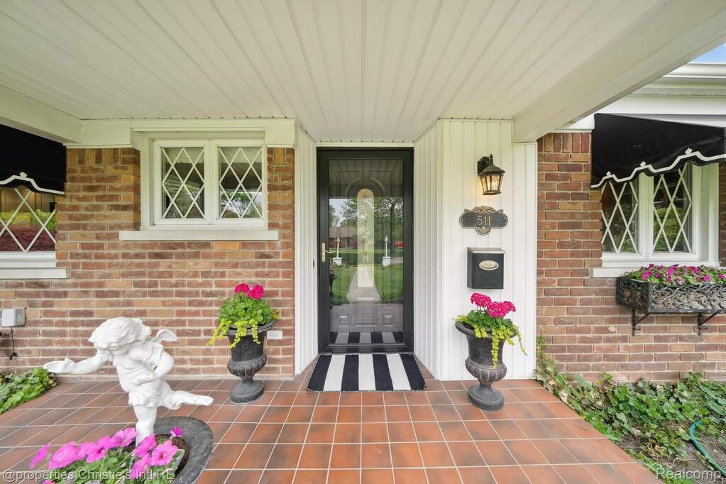 Doorway to property with covered porch and brick siding