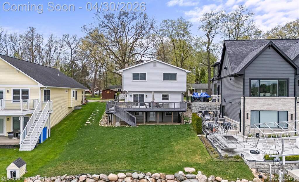 Back of property featuring a newer composite deck flat lawn to the lake.