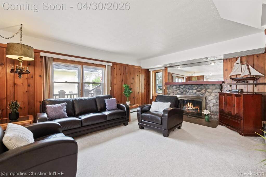 Carpeted living area with wooden walls and a stone fireplace