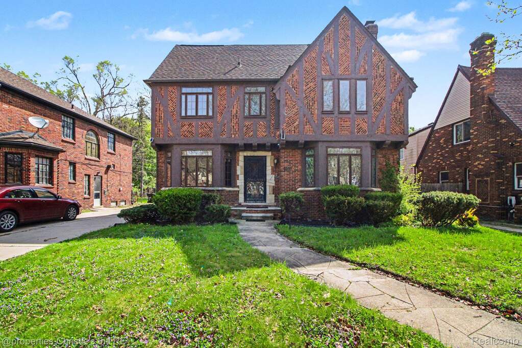 Tudor home featuring a front yard and brick siding