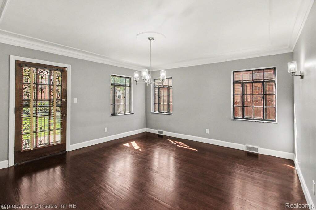Unfurnished dining area with dark wood-style flooring, a chandelier, and crown molding