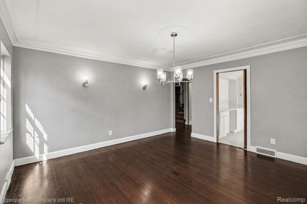 Unfurnished dining area with dark wood-style floors, ornamental molding, and suspended lighting