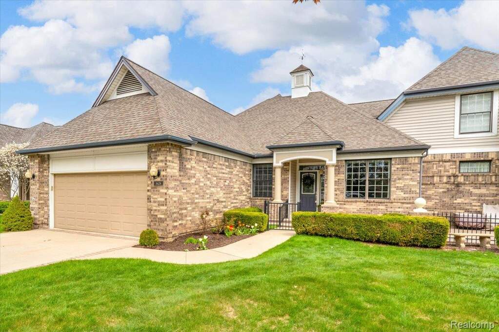 View of front of home with a garage, a front yard, brick siding, and concrete driveway