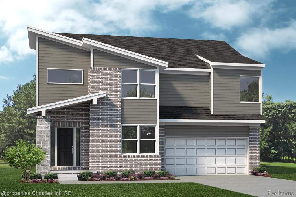 View of front facade featuring concrete driveway, brick siding, a garage, and a front lawn
