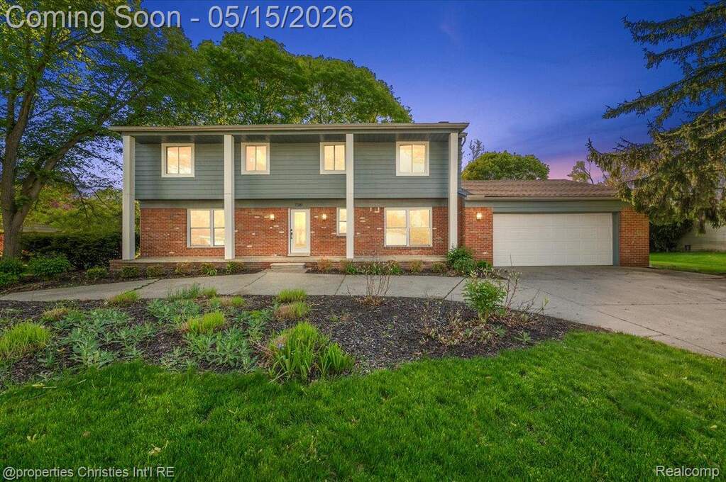 Colonial inspired home with an attached garage, concrete driveway, brick siding, and a front yard