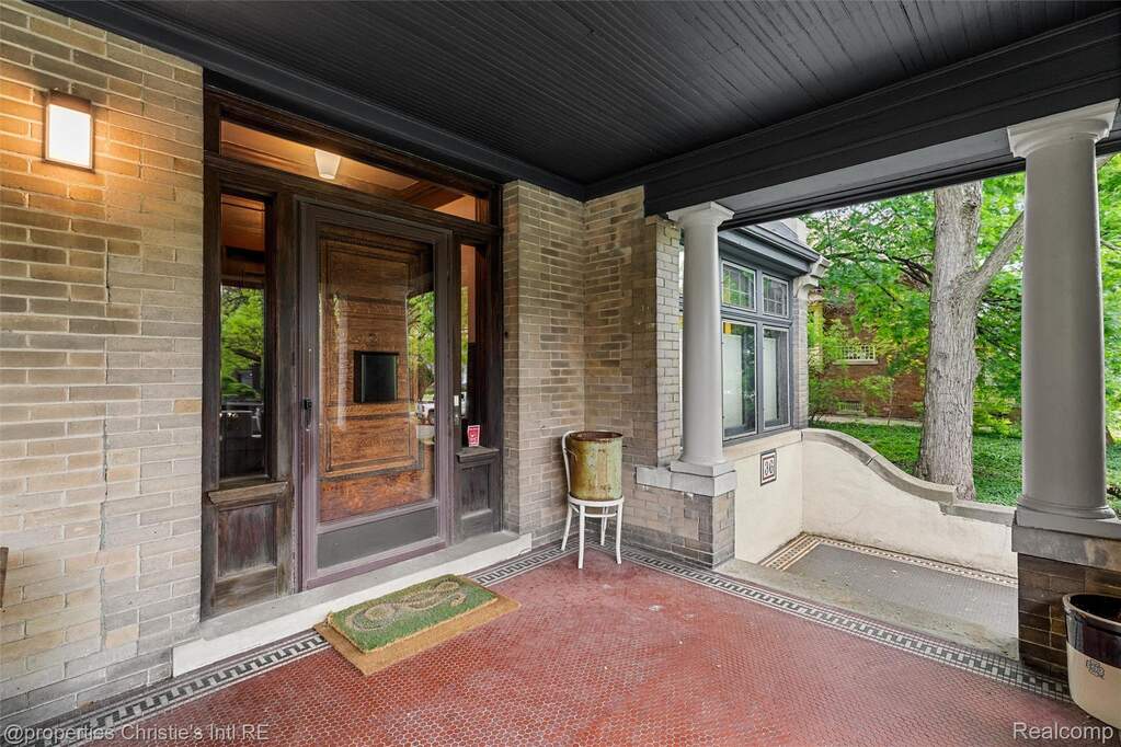 Doorway to property featuring a porch and brick siding