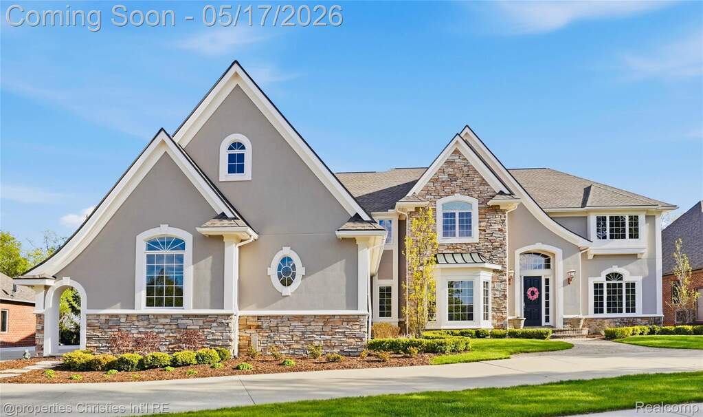 View of front of property with stone siding, stucco siding, and a standing seam roof