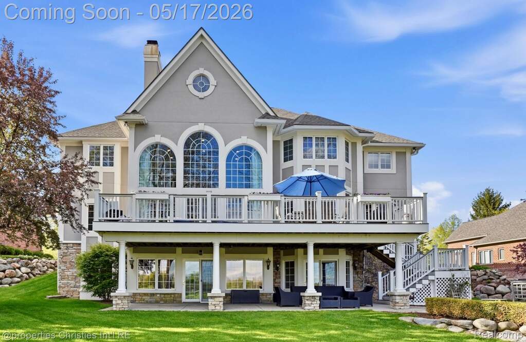 Back of house with a chimney, a lawn, a wooden deck, stucco siding, and stone siding