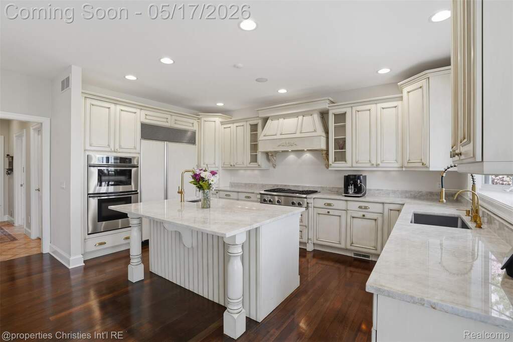 Kitchen with light stone countertops, recessed lighting, a kitchen bar, a center island, and glass fronted cabinets