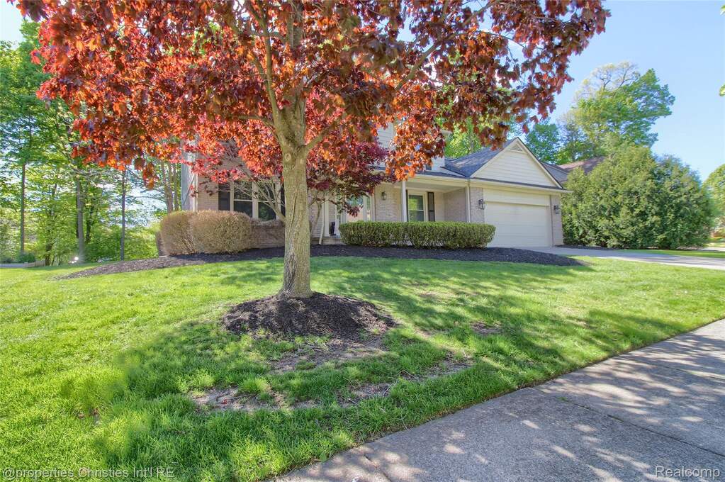 View of front of house with a front lawn, an attached garage, brick siding, and driveway