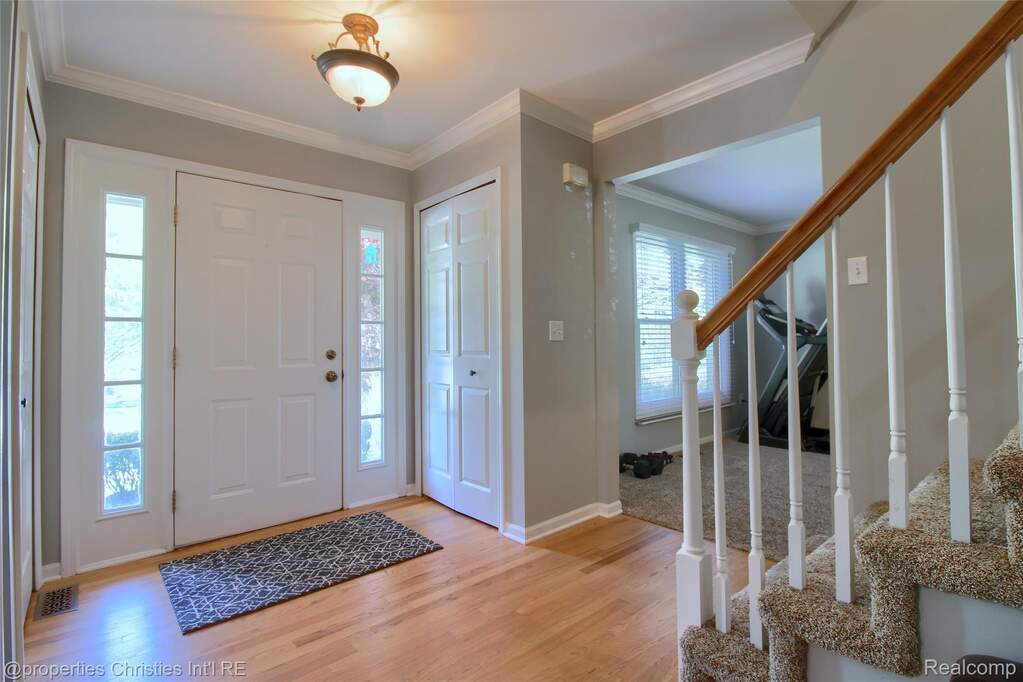 Entrance foyer featuring light wood-style floors and crown molding