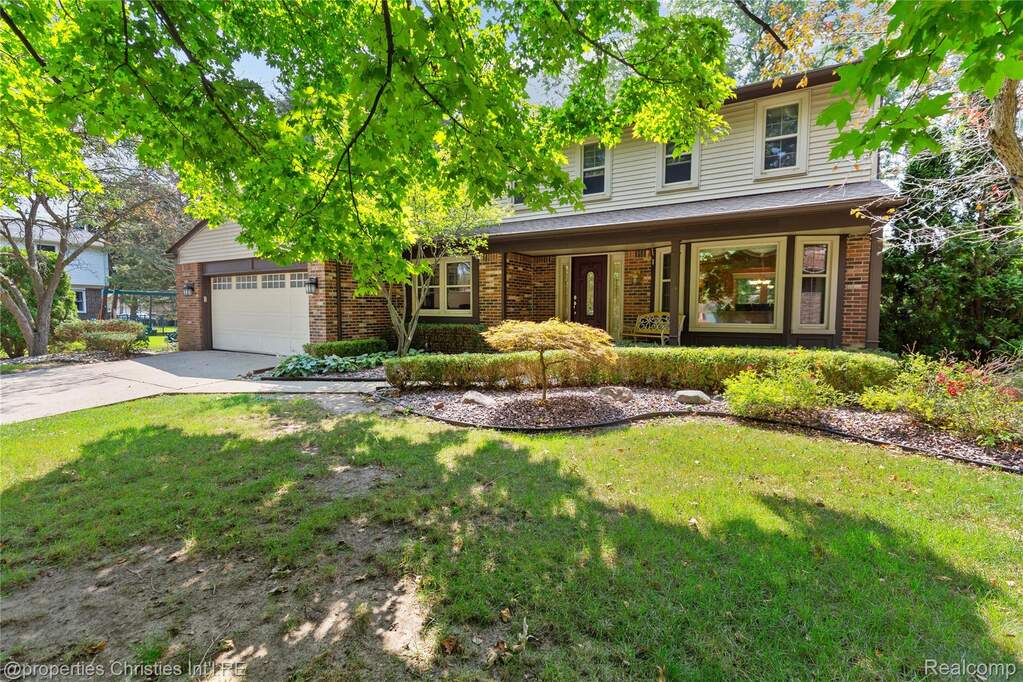 Traditional-style home with brick siding, a front lawn, an attached garage, and concrete driveway