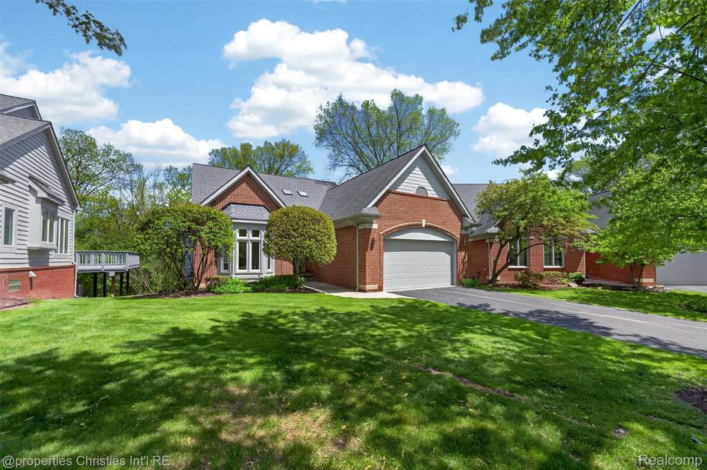 View of front of home with a front yard, a garage, asphalt driveway, and brick siding