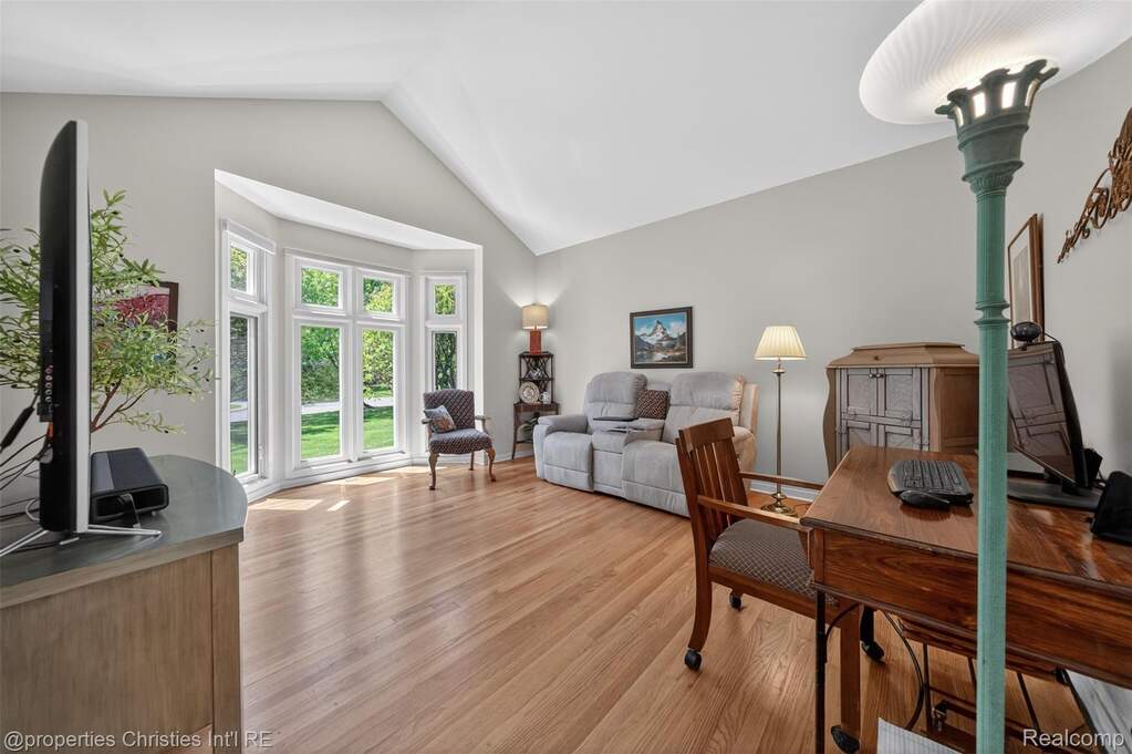 Library featuring light wood floors, vaulted ceiling and wall of windows